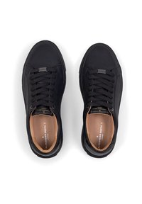 Sneaker neri con una texture liscia e punta arrotondata, dotati di lacci, un interno beige e un accento in metallo con logo sulla linguetta.