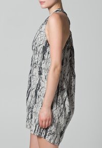 Vestido con estampado gráfico en gris y negro; diseño sin mangas, corte suelto, con patrones texturizados abstractos y escote redondo.