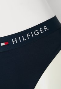 Námornícky bikiny spodok z bavlnenej zmesi s logom v páse, na ktorom je písané "HILFIGER" bielymi písmenami a malým červeným a bielym emblémom.