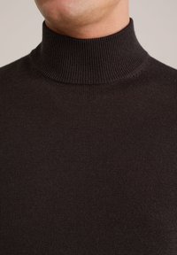 Pulover turtleneck de culoare maro închis, cu o textură cu nervuri, guler înalt și un design ajustat, punând accent pe simplitate și confort.