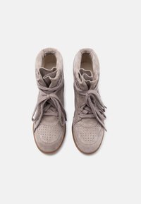 Ζευγάρι από μπεζ μπότες αστραγάλου από σουέντ με κορδόνια δεμένα σε φιόγκους, με διάτρητο σχέδιο στη μύτη και μαλακό επενδυμένο γιακά, εμφανιζόμενες από πάνω σε λευκό φόντο.