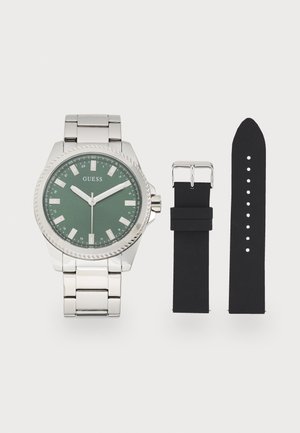 Montre en acier inoxydable argenté avec un cadran vert, des index horaires blancs et une lunette texturée. Comprend un bracelet en caoutchouc noir pour un changement.