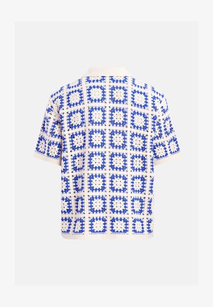 Kortærmet strikket skjorte med blå og hvide hæklede firkantmønstre, der har en åbenvævet struktur og en krave.