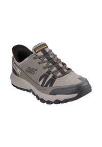 Scarpa da ginnastica grigia con tomaia in mesh, dettagli neri, suola testurizzata e logo. Design resistente, adatto ad attività all'aperto.