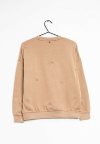 Beige sweatshirt hanging on black hanger, featuring small embroidered bird motifs scattered across the fabric.