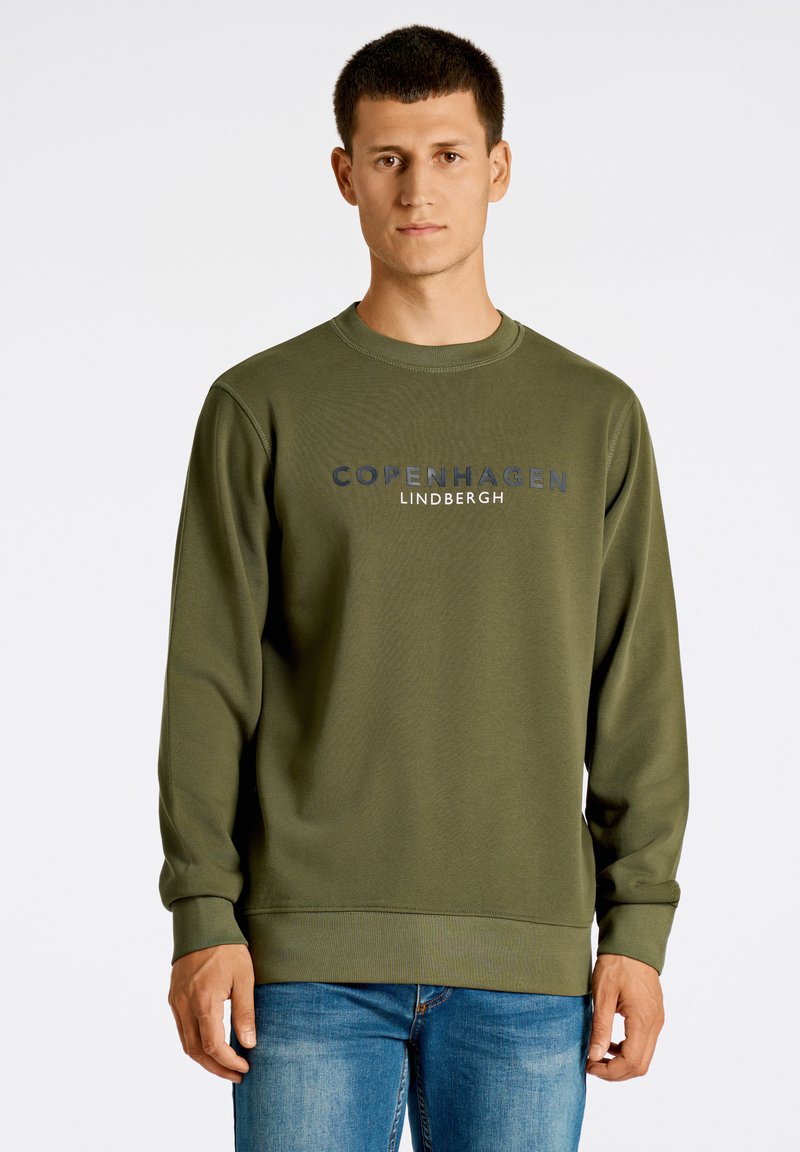 Olivgrön sweatshirt i ett mjukt, texturerat tyg. Har rundad halsringning och ribbade ärmslut, med "COPENHAGEN LINDBERGH" tryckt i marinblått.
