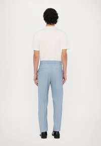 Vaaleansiniset raidalliset housut, jotka on valmistettu sileästä kankaasta, kahdella takataskulla ja tavallisella vyötäröhihnalla. Yhdistetty yksinkertaisen valkoisen T-paidan kanssa.