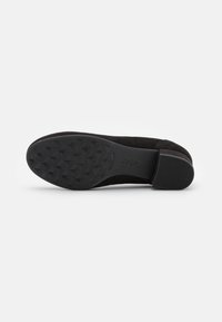 Semelle de chaussure en suède noir avec un motif de grip texturé et des accents lisses. Présente un léger talon et un design de bout arrondi.