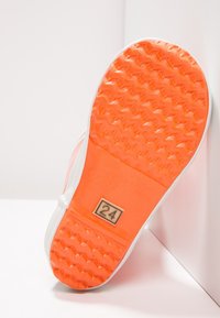 Pomarańczowa gumowa podeszwa buta z teksturowanym wzorem antypoślizgowym i białą krawędzią. Posiada prostokątną etykietę z numerem "24."