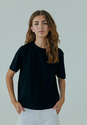 Zwarte t-shirt met korte mouwen, gemaakt van zachte stof met een ronde hals. Heeft een relaxte pasvorm en minimale stikseldetails.