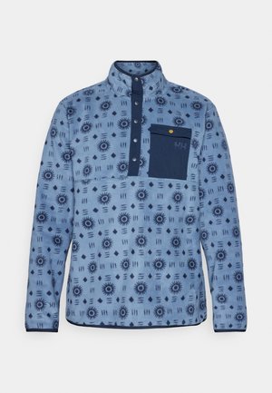 Mėlynas fliso megztinis su geometriniu raštu, ketvirčio užtrauktuku ant kaklo ir tamsiai mėlyna kišene. Yra spaustukai ir tekstūruotas audinys.