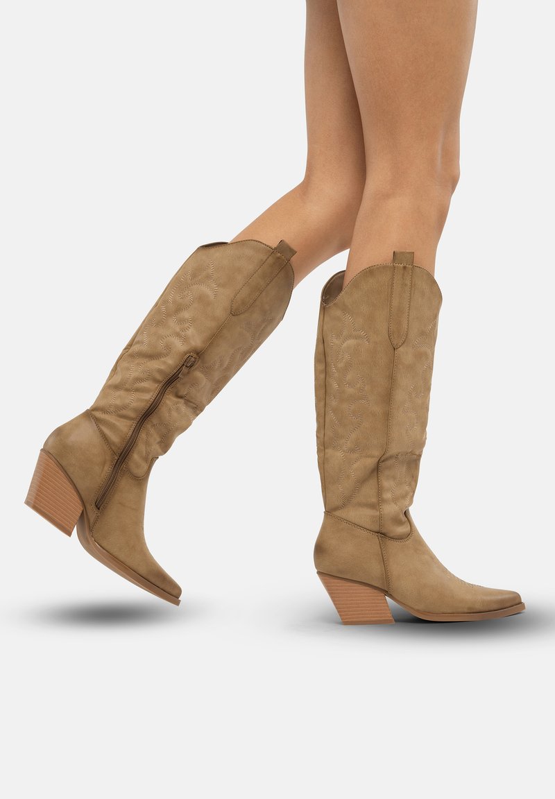 Botas de vaquero marrones con un eje texturizado, cremallera lateral y tacón en capas. Patrones de costura decorativa adornan la parte superior de la bota.
