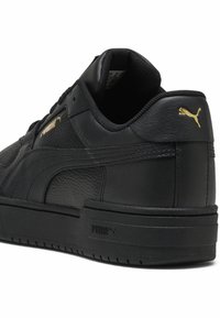 Baskets en cuir noir à finition texturée, avec des accents dorés du logo Puma, un col rembourré et une semelle épaisse en caoutchouc.