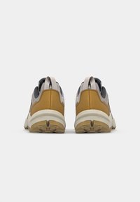 Szare i brązowe sneakersy z teksturowaną cholewką, wzmocnionym zapiętkiem oraz gumową podeszwą. Posiadają uchwyty z tyłu oraz wielopatternową bieżnię.