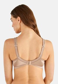 BH i nude färg med justerbara axelband och bakknäppning, med ett mjukt och slätt material samt diskreta sömmar.