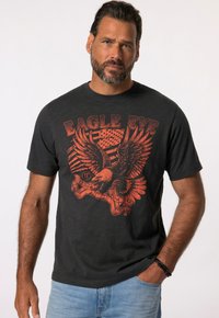 Zwarte ronde hals t-shirt met een rode adelaar grafiek en de tekst "EAGLE EYE," met een vervaagd ontwerp en zachte textuur. Korte mouwen, ontspannen pasvorm.