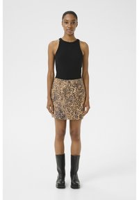 Schwarzes geripptes Tanktop und ein Rock mit Leopardenmuster, kombiniert mit knielangen schwarzen Stiefeln. Weicher Stoff mit figurbetonendem Design, das ein dezentes Logo zeigt.