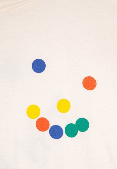 Camiseta de algodón color beige con siete puntos coloridos: dos azules, tres amarillos, uno naranja y uno verde, dispuestos en un patrón similar a una cara sonriente.