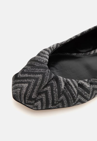 Black and gray patterned flat shoe with a rounded toe, featuring a zigzag design and smooth inner lining, constructed from soft fabric.