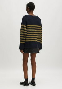 Dunkelblau und olivgrün gestreifter, grob gestrickter Pullover mit lässiger Passform, rundem Ausschnitt und überschnittenen Schultern, kombiniert mit einem schwarzen Minirock.