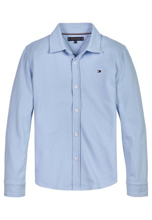 Jasnoniebieska koszula na długi rękaw z kołnierzykiem, małym logo Tommy Hilfiger na klatce piersiowej i białymi guzikami na przodzie.