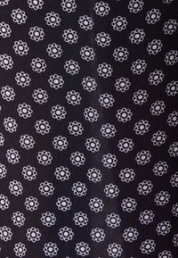 Tissu noir avec petits motifs floraux blancs uniformément espacés en rangées et colonnes.