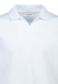 Biała koszulka polo o luźnym kroju, z dekoltem w serek i miękką bawełnianą fakturą. Płaski kołnierzyk i minimalistyczny design, bez wzorów i ozdób.