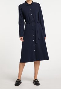 Abito camicia navy realizzato in tessuto morbido, con maniche lunghe, vita con cintura e gonna svasata con bottoni bianchi.