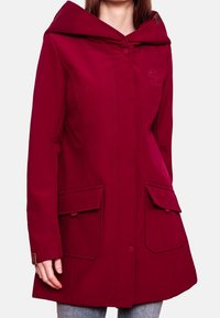 Veste à capuche rouge avec une fermeture à bouton, deux poches avant et des coutures tonales. Fabriquée dans un matériau lisse et résistant aux intempéries.