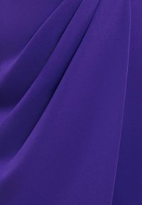 Violetti kangas, jossa on sileä rakenne, pehmeät laskokset ja lempeät taitteet, esittelee rikkaita värejä ja kevyttä materiaalia.