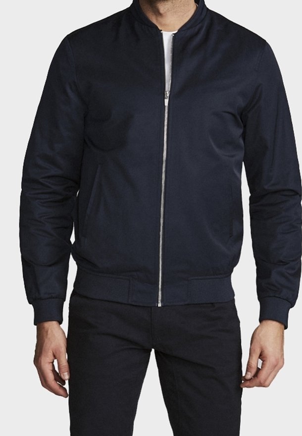 Chaqueta bomber azul marino hecha de tela lisa, con cremallera frontal, cuello y puños acanalados. Se pueden ver dos bolsillos laterales.