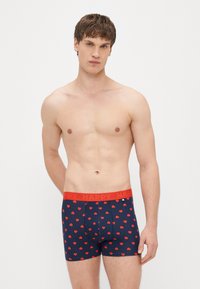 Tmavomodré boxerské trenky s červeným vzorom srdiečok, s červeným elastickým pásom s nápisom „HAPPY“. Vyrobené z mäkkej, elastickej tkaniny.