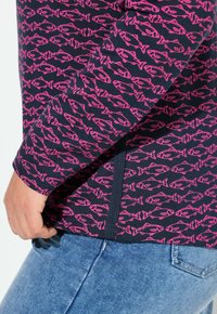 Sininen pitkähihainen paita, jossa on vaaleanpunaisia kalakuvioita. Paidan pyöreä pääntie ja sivupaneelin yksityiskohdat. Valmistettu kevyestä ja joustavasta kankaasta.