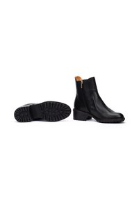 Bottines en cuir noir avec une fermeture éclair latérale, semelle en caoutchouc texturé, talon bloc bas et un intérieur en accent marron.