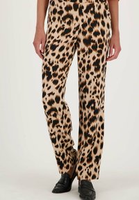 Panterprint broeken in beige en zwart, met een wijd beenontwerp en een zachte textuur, gecombineerd met zwarte loafers.