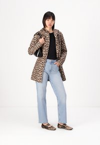 Leopard-print coat with a hood, black top, light blue jeans, and patterned flats. Features a black handbag. Smooth fabric, relaxed fit.