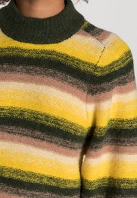 Sweter z dzianiny z wysokim zielonym kołnierzem, z poziomymi paskami w kolorach żółtym, zielonym, jasnoróżowym i kremowym. Miękka tekstura, swobodny design.