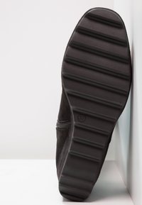 Mustat mokka-tossut, joissa on teksturoitu kumipohja, sivu vetoketjulla helppoa pukemista varten ja hieman pyöristetty kärkimuoto. Koko 37.