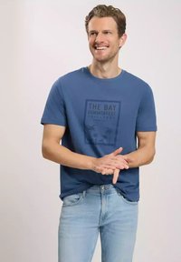Niebieska bawełniana koszulka z prostokątnym nadrukiem z tekstem "THE BAY SUMMERFEST CHALLENGE". Krótkie rękawy i okrągły dekolt.
