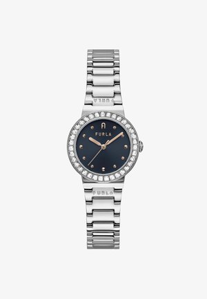 Hõbedast metallkell, millel on tume sinine kellaplaat, kristallidekaunistustega raamis ja kuldsetes toonides käed. Omab lingisidemetega käevõru ja toodetud brändi logo reljeefset kujutist.