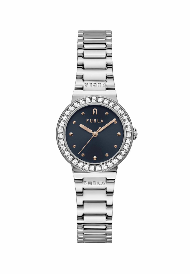 Reloj de pulsera de metal plateado con un dial de color azul marino, bisel adornado con cristales y manecillas en tono dorado. Incluye una pulsera de eslabones y un logo de marca en relieve.