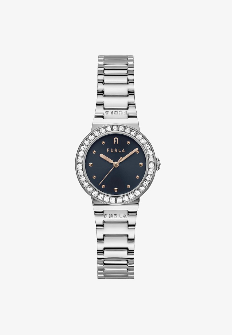 Hõbedast metallkell, millel on tume sinine kellaplaat, kristallidekaunistustega raamis ja kuldsetes toonides käed. Omab lingisidemetega käevõru ja toodetud brändi logo reljeefset kujutist.