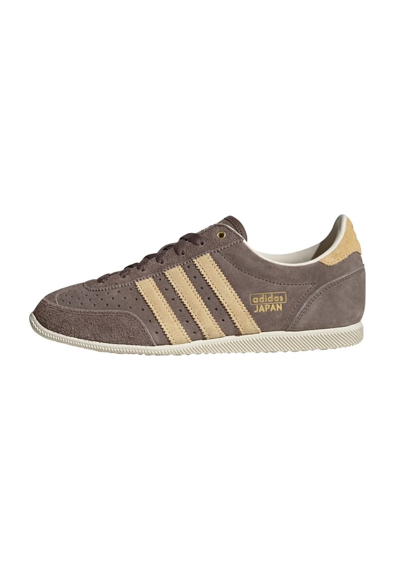 Brun mockasneaker med beige tre-randig design, perforerade detaljer på tån och en texturerad gummisula. Guld "adidas JAPAN"-logotyp som accent.