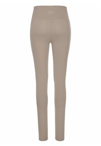 Beige leggings met een hoge tailleband, gemaakt van rekbare stof, met een gladde textuur en een logotag op de achterkant in het midden.
