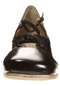 Chaussure en cuir noir avec un bout pointu, un design découpé et des lacets croisés. Texture lisse et brillante avec une semelle plate.
