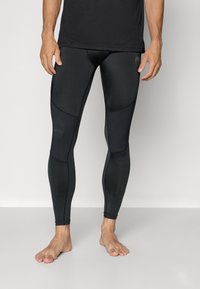 Svarta träningsleggings tillverkade av stretchigt material, med en åtsittande design som har paneldetaljer och ribbat mönster längs sidorna.