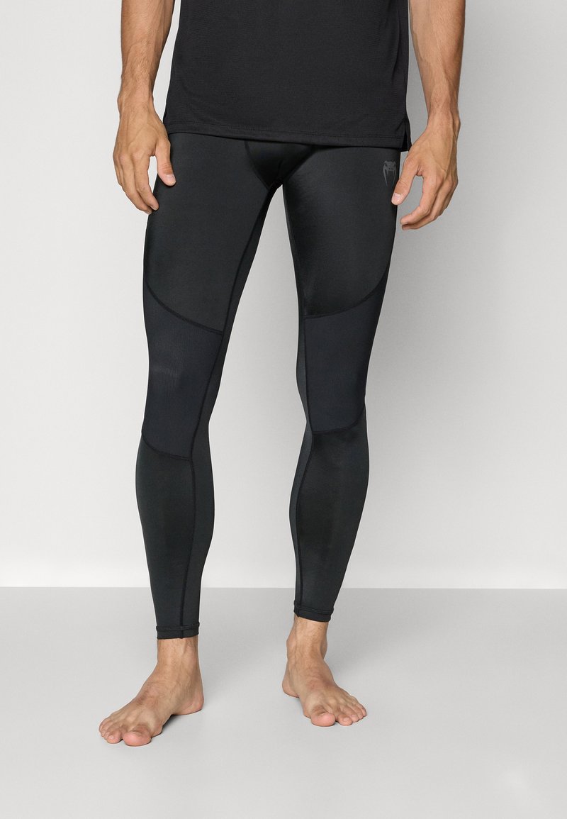 Svarta träningsleggings tillverkade av stretchigt material, med en åtsittande design som har paneldetaljer och ribbat mönster längs sidorna.
