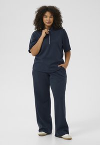 Navy pullover with short sleeves and a zip collar, paired with matching wide-leg pants. Soft fabric with a smooth texture and white accents.