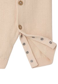 Gestrickte Strickjacke in sanftem Pfirsich mit Holzknöpfen und Druckknopfverschluss, versehen mit gerippten Bündchen und Saum, die eine strukturierte Oberfläche bieten.