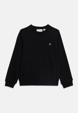 Sort langærmet sweatshirt med rund hals og ribkant ved manchetter og kant, med en lille hvid "cK" logo patch på venstre bryst.